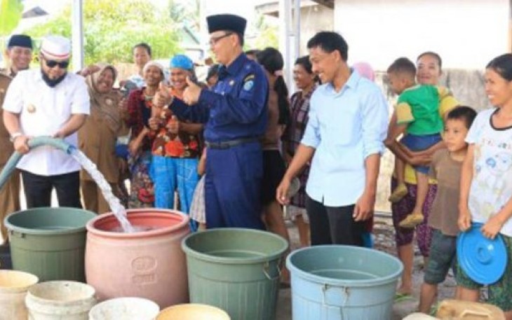 Wali Kota Bengkulu Helmi Hasan Mengenakan Peci Putih Sedang Menuang Air Kedalam Ember 