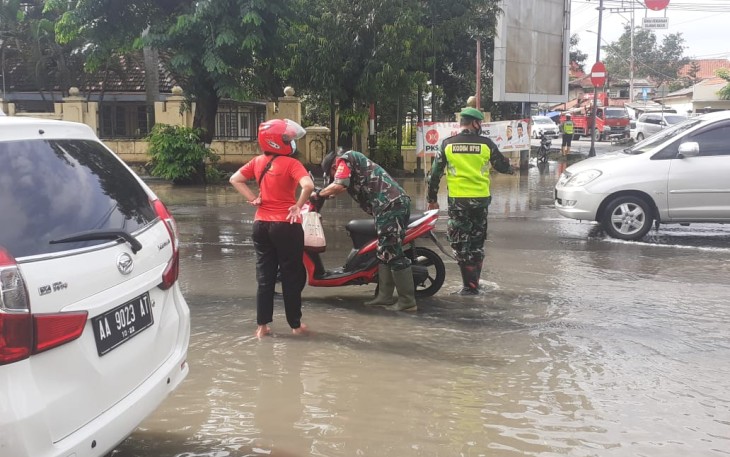 Bati Ops  Kodim 0715/Kendal Pelda Riyanto membantu menghidupkan motor seorang Ibu yg sedang melintas di depan Makodim 0715/Kendal yang terkena genangan air banjir.