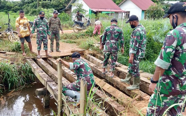 Personel TNI yang tergabung dalam Satgas Pamtas RI-MLY Yonif 407/PK, Pos Sei Beruang membantu memperbaiki jembatan yang rusak di Dusun Sei Beruang, Desa Sei Tekam, Kecamatan Sekayam, Kabupaten Sanggau, Kalbar. Senin (15/02/2021).