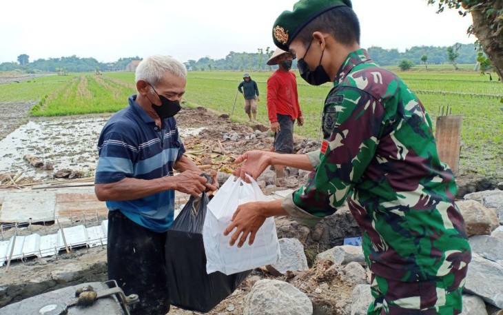 Personel Yonif Mekanis Raider 413/Bremoro membagikan nasi kotak kepada masyarakat dalam kegiatan bhakti sosial "Kostrad Peduli"