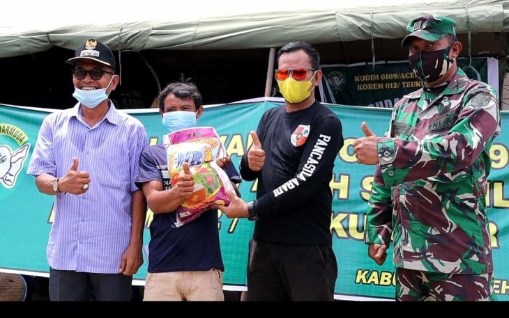 Pj Kades Rantau Gedang, Irwansyah Rizal (tengah) saat menyerahkan bantuan beras kepada salah seorang warga peserta vaksin setempat
