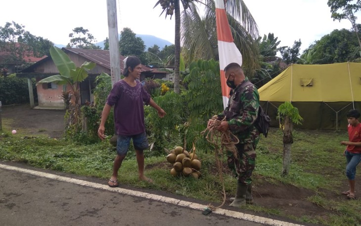 Personil satgas TMMD bersama warga usai manjat pohon kelapa