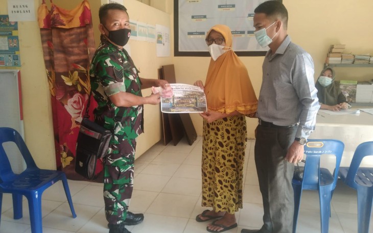 Babinsa Pulo Sarok Serma MR.Munthe (kiri) didampingi Perangkat Desa Pulo Sarok, saat menyerahkan BLT-DD kepada penerima.