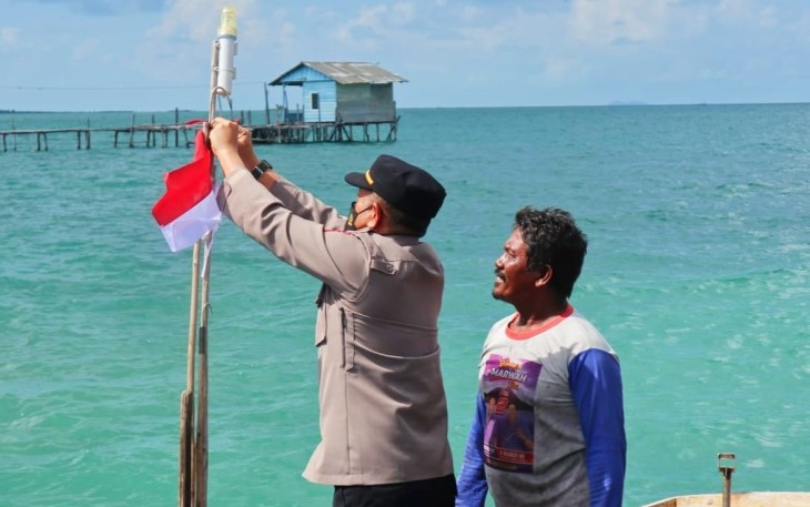 Kapolsek saat membagikan bendera merah putih diatas pompong milik nelayan