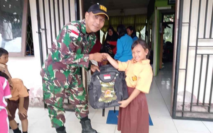 Personel satgas saat memberikan bantuan tas sekolah