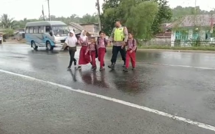 Polisi saat membantu anak-anak menyebrang jalan.