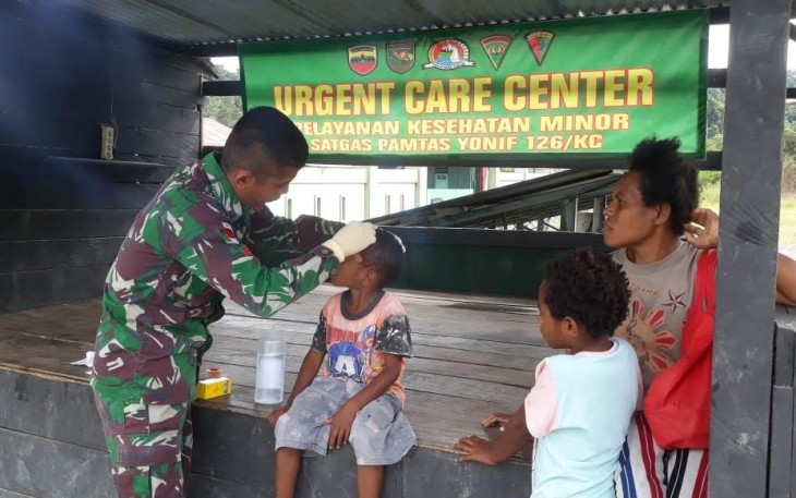 Satgas Pamtas Yonif 126/Kala Cakti saar mengobati Anton Ibe (6) yang mengalami luka di dahi akibat terjatuh saat bermain bersama teman-temannya.
