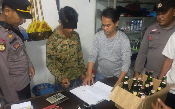 Polisi saat menyuruh pemilik warung menandatangani surat perjanjian tidak jual miras ilegal lagi.