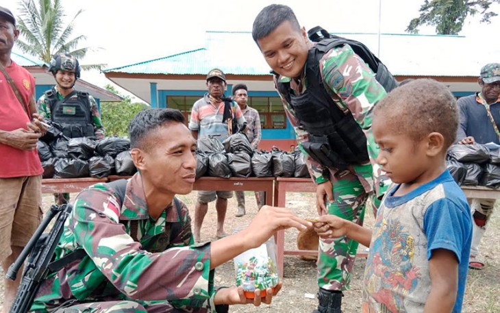 Anggota saat memberikan makanan kepada seorang anak di perbatasan.