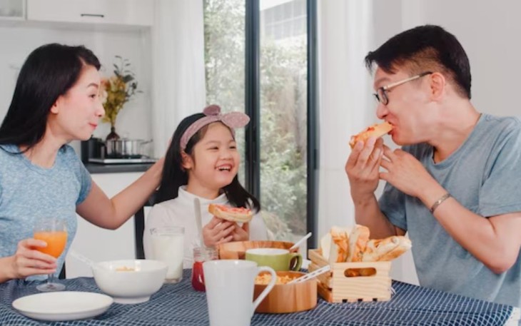 Ilustrasi. Foto: Asian mom, dad, and daughter feeling happy talking together while eating. (Sumber: medcom.id)