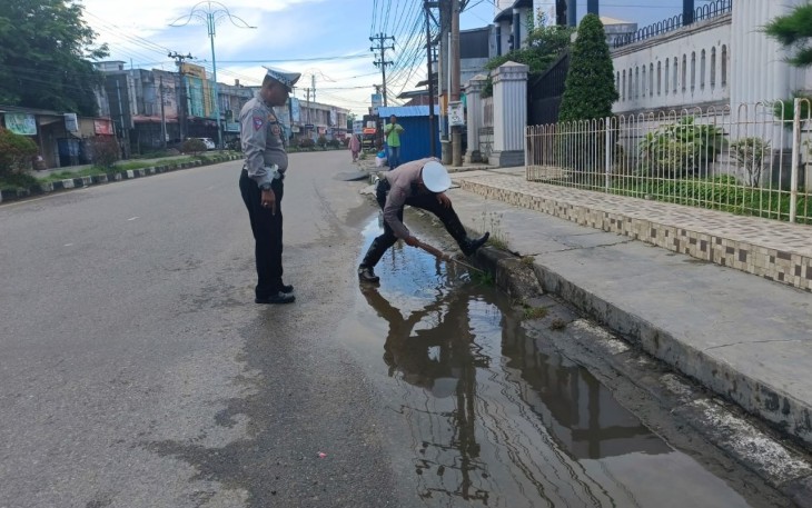 Anggota Satlantas Polres Aceh Timur membersihkan saluran pembuangan