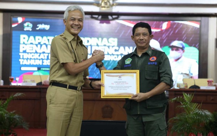 Kepala BNPB Letjen TNI Suharyanto (kanan) secara simbolis menyerahkan bantuan Dana Siap Pakai (DSP) dengan total 4,25M yang diterima langsung oleh Gubernur Jawa Tengah Ganjar Pranowo (kiri) untuk bantuan operasional penanganan darurat banjir, Senin (2/1).