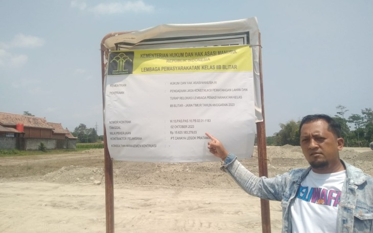 Salah Seorang Tokoh Masyarakat Setempat Saat Menunjukkan Papan Profil Pengerja Proyek Relokasi Lapas Kelas II B Blitar