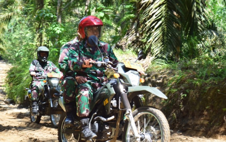 Babinsa Patroli dengan motor trail pengecekan badan jalan di lokasi TMMD menjelang waktu peresmian.