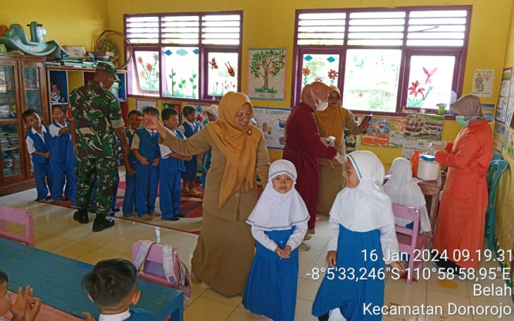 Babinsa Koramil 0801/11 Donorojo Kodim 0801/Pacitan Serda Yudiyanto mendampingi petugas kesehatan memberikan imunisasi polio terhadap 27 siswa di Sekolah TK Harapan, Desa Belah, Kec. Donorojo, Kab. Pacitan, Selasa (16/01/2024)