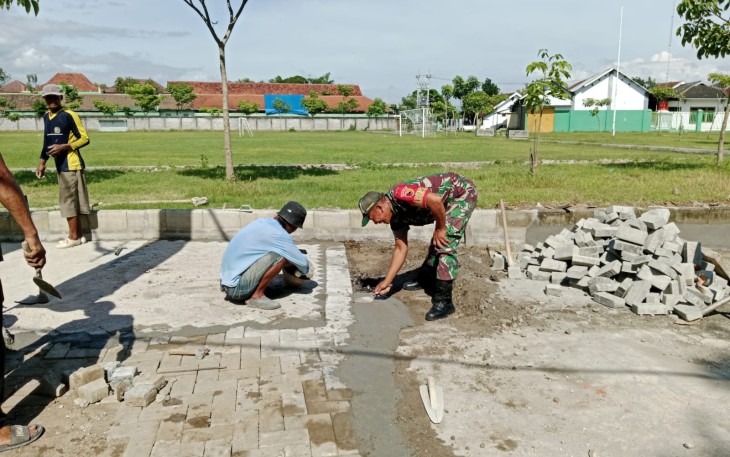 Babinsa Kodim Ponorogo saat Bantu Warga Pasang Pafing Jalan