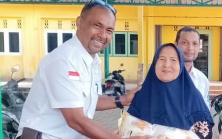 Camat Tambelan Asmawi saat menyerahkan beras pada ibu Lansia