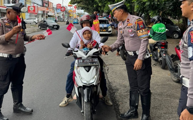 Personil Polres Bitung saat membagikan bendera merah putih kepada pengguna jalan