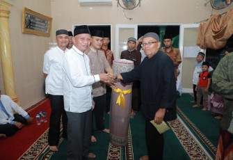 Plt. Bupati Asahan, Surya saat menyerahkan bantuan kepada Ketua BKM Musholla Ikhwanul Munir.