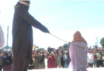 Algojo ketika menghayunkan rotan kearah punggung seorang perempuan terpidana khalwat pada awal agustus lalu di halaman Mesjid Agung Bireuen.