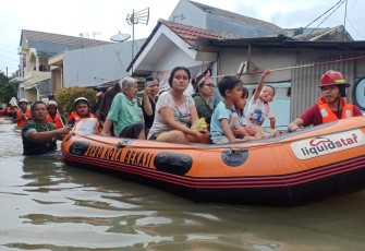 Serda Agus Babinsa Koramil 01/Kranji Evakuasi warga Banjir di Kelurahan Pejuang.
