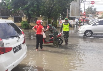 Bati Ops  Kodim 0715/Kendal Pelda Riyanto membantu menghidupkan motor seorang Ibu yg sedang melintas di depan Makodim 0715/Kendal yang terkena genangan air banjir.