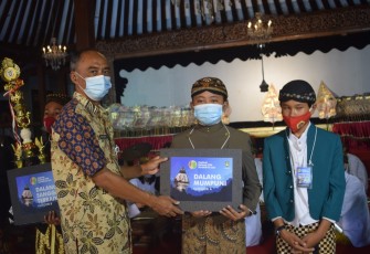 Kepala Dinas Kebudayaan Kota Surakarta, Agus Santoso saat menyerahkan piala Dalang Mumpuni dalam Festival Dalang Cilik Kota Surakarta 2021 Kategori A untuk siswa SD