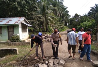 Bhabinkamtibmas Gotong Royong Bersama Warga Timbun Jalan Berlubang