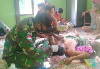 Satgas Pamtas RI-Malaysia Yonif 407/PK Pos Muakan mengobati Jeli Ridwan (27) warga Desa Muakan Petinggi, Kec. Ketungau Hulu Kab. Sintang yang mengalami musibah terkena dahan pohon saat memotong kayu.