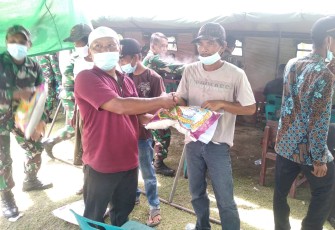 Kades Teluk Rumbia Kamaluddin (kiri) memberikan beras kepad warga usai menjalani vaksinasi yang dilaksanakan didesa setempat