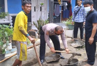 Bripka Adhi Firmansyah bergotong royong bersama warga membersihkan parit di wilayah Kasokandel 