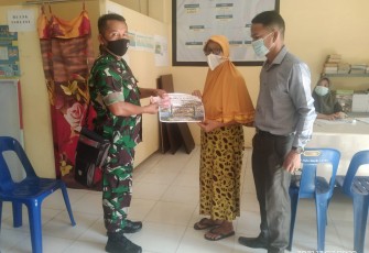 Babinsa Pulo Sarok Serma MR.Munthe (kiri) didampingi Perangkat Desa Pulo Sarok, saat menyerahkan BLT-DD kepada penerima.