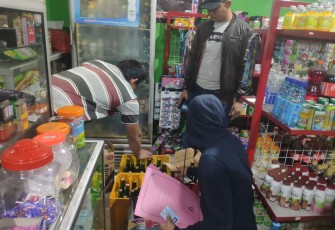 Anggota Sat Reskrim Polres Karanganyar tengah mengamankan puluhan botol miras dari toko kelontong milik S, di wilayah Pulosari, Kebakkramat, Kabupaten Karanganyar, pada Senin (29/8/2022) dini hari. (Foto : Istimewa).