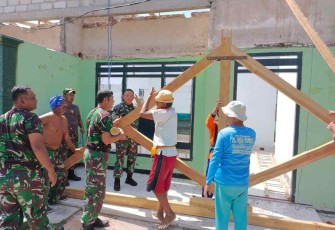 Dandim saat membantu angkat palang kuda atap bersama anggota