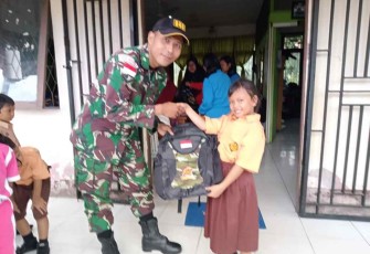 Personel satgas saat memberikan bantuan tas sekolah