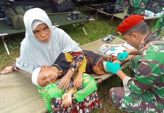 Prajurit Kopassus saat mengobati luka anak korban 