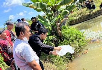 Ilyas Akbar Almadani saat menebar bibit ikan wader bersama warga di sungai Desa Gentungan, Mojogedang, Karanganyar, Minggu (3/7/2022).
