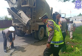 Anggota Satlantas saat turun langsung mencangkul dan meratakan batu pecah bercampur semen pada bagian jalan yang rusak dan berlubang.