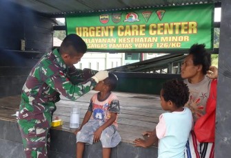 Satgas Pamtas Yonif 126/Kala Cakti saar mengobati Anton Ibe (6) yang mengalami luka di dahi akibat terjatuh saat bermain bersama teman-temannya.