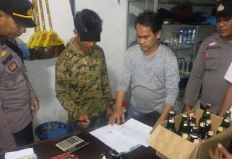 Polisi saat menyuruh pemilik warung menandatangani surat perjanjian tidak jual miras ilegal lagi.