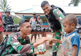 Anggota saat memberikan makanan kepada seorang anak di perbatasan.