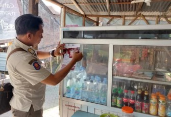 Anggota Satpol PP Kabupaten Tulungagung saat menempelkan stiker larangan menjual rokok ilegal di warung