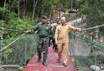 Danrem 023/KS Kolonel Inf Lukman Hakim bersama Bupati Tapanuli Utara Nikson Nababan saat melintasi jembatan gantung usai peresmian, Selasa (18/7)