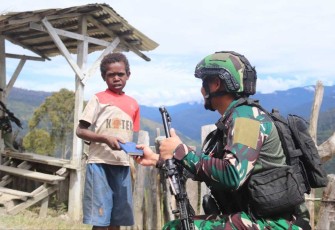 Prajurit satgas Yonif PR 330 saat memberikan Alkitab warga Intan Jaya, Kamis (9/11)