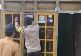 Bhabinkamtibmas Saat Dampingi Pemasangan Stiker Penerima Bansos.