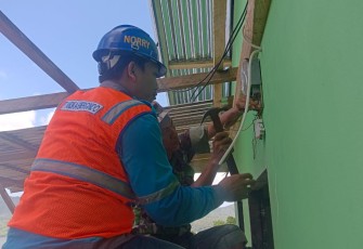Satgas TMMD bersama pegawai PLN saat memasang instalasi listrik