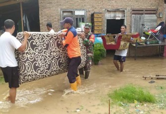 Tim BPBD Kab. Pringsewu membantu warga mengevakuasi diri dan harta benda menyusul banjir yang merendam akibat meluapnya Sungai Way Tebu, Jumat (24/5) malam
