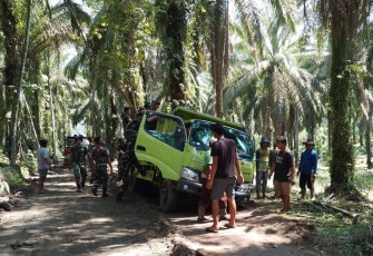 Satgas TMMD dan warga mengevakuasi Truk yang terperosok di badan jalan. 