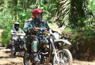Babinsa Patroli dengan motor trail pengecekan badan jalan di lokasi TMMD menjelang waktu peresmian.