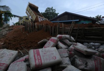 Truk milik Dinas Pekerjaan Umum menumpahkan material tanah untuk menutup tanggul yang jebol di wilayah Tanjung Pura, Kabupaten Langkat, Sumatra Utara, Jumat (12/12).